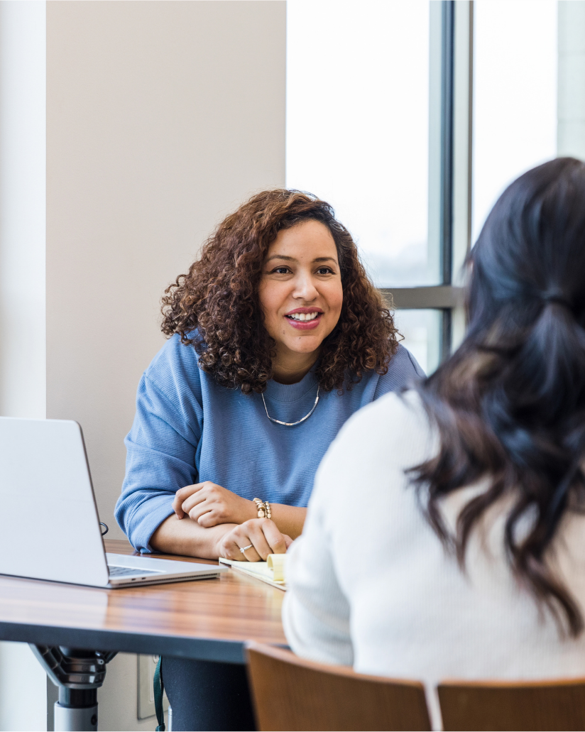 A case manager meeting with a client at a table with a laptop